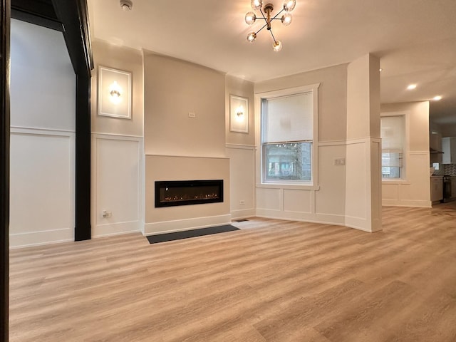 4409 S Prairie Ave, Chicago, IL 60653 - unfurnished living room with a decorative wall, a glass covered fireplace, light wood-type flooring, a wainscoted wall, and recessed lighting