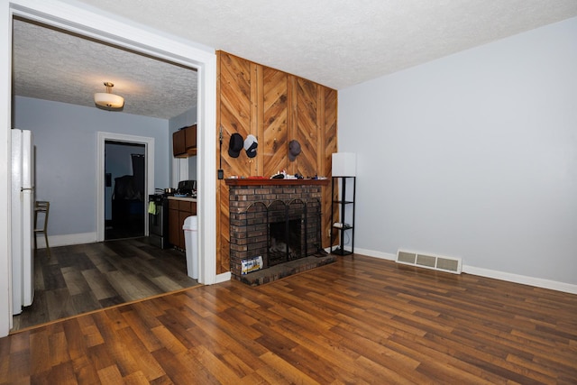 211 E Mulberry St, Bloomington, IL 61701 - unfurnished living room with dark wood finished floors, a textured ceiling, and a brick fireplace