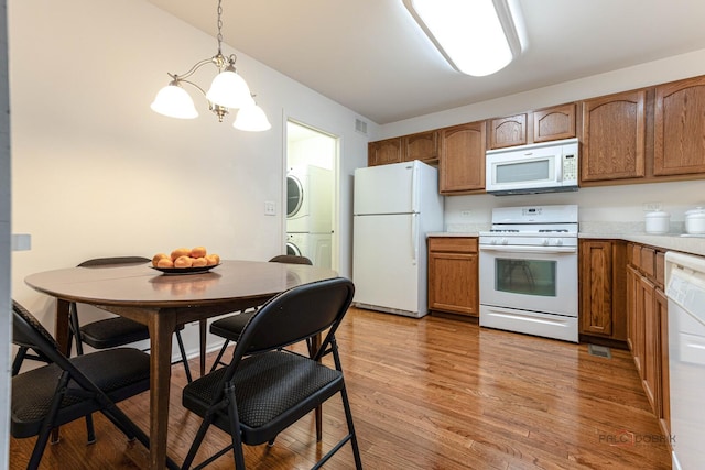 32374 N Allegheny Way Unit 0, Lakemoor, IL 60051 - kitchen with white appliances, stacked washer / dryer, light countertops, a chandelier, and light wood-style flooring