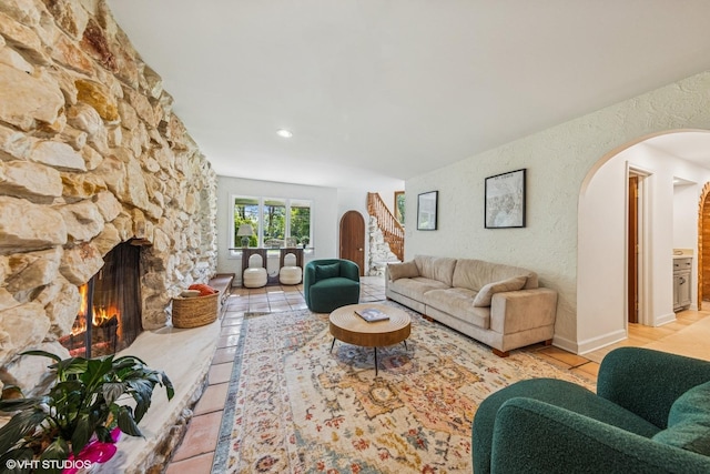 5525 Lee Ave, Downers Grove, IL 60515 - living room featuring arched walkways, a stone fireplace, a textured wall, and light tile patterned floors