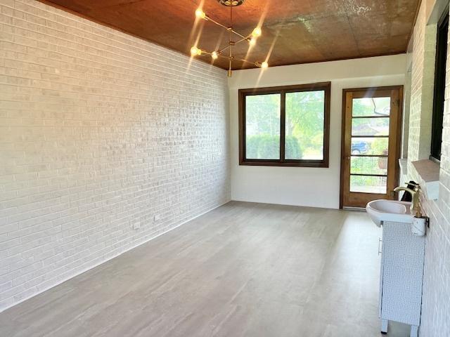 909 N Brinton Ave, Dixon, IL 61021 - dining space with wood finished floors, brick wall, plenty of natural light, and a chandelier