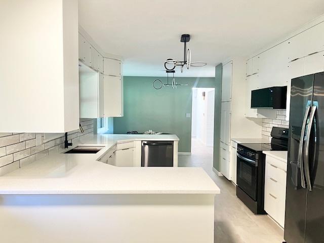 909 N Brinton Ave, Dixon, IL 61021 - kitchen with fridge with ice dispenser, black electric range oven, stainless steel dishwasher, and decorative backsplash