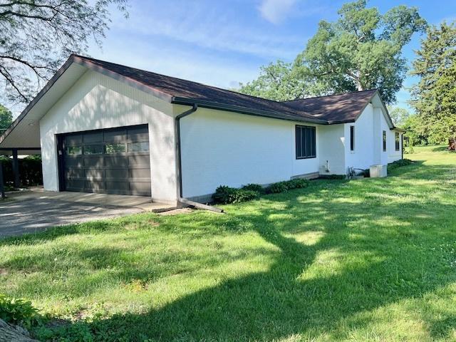 909 N Brinton Ave, Dixon, IL 61021 - view of home's exterior featuring a garage, stucco siding, a yard, and driveway
