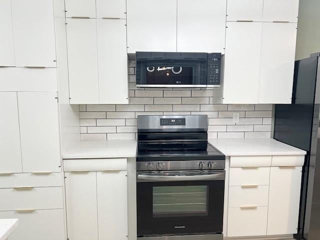 909 N Brinton Ave, Dixon, IL 61021 - kitchen with stainless steel electric range, black microwave, freestanding refrigerator, light countertops, and backsplash
