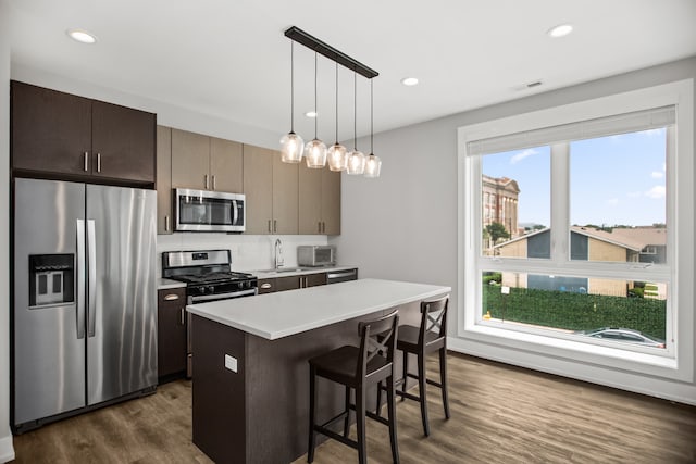 2304 W Jackson Blvd Unit 2W, Chicago, IL 60612 - kitchen with stainless steel appliances, dark wood-type flooring, a breakfast bar, light countertops, and a center island