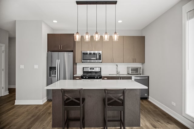 2304 W Jackson Blvd Unit 2W, Chicago, IL 60612 - kitchen featuring stainless steel appliances, light countertops, a kitchen island, dark wood-type flooring, and a breakfast bar area