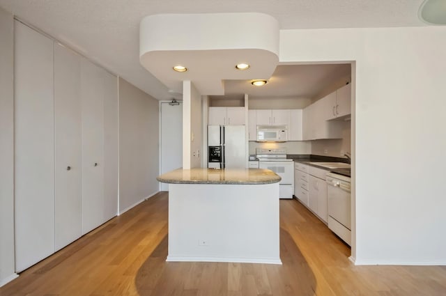 405 N Wabash Ave Unit 3611, Chicago, IL 60611 - kitchen featuring white appliances, light wood-style flooring, a center island, white cabinets, and recessed lighting