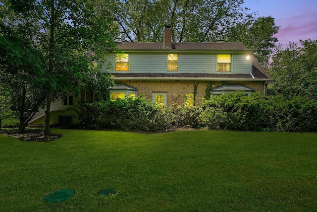 600 Riverwoods Rd, Mettawa, IL 60045 - back of house at dusk with a lawn, a chimney, and brick siding
