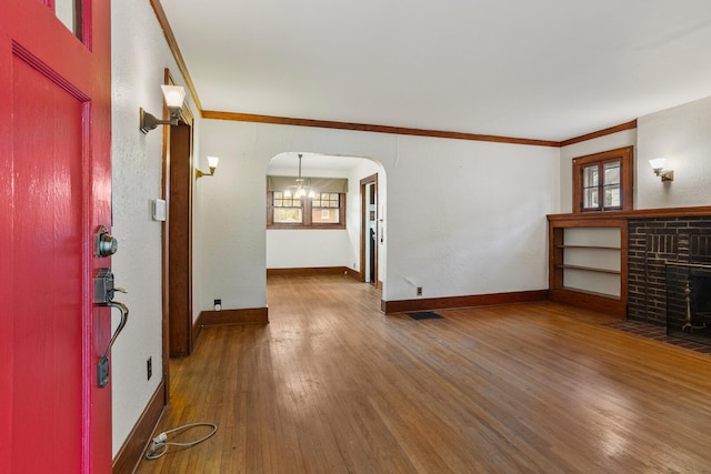 705 Arlington Ct, Champaign, IL 61820 - unfurnished living room with wood finished floors, ornamental molding, arched walkways, and a brick fireplace