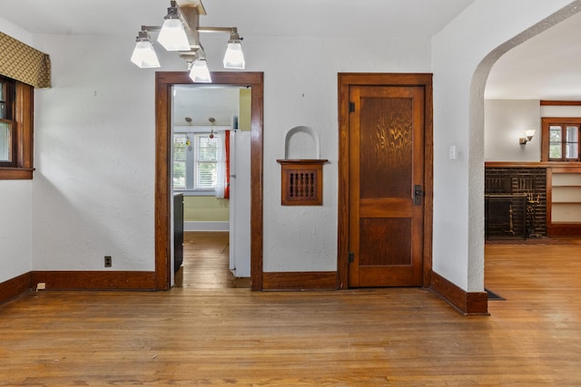 705 Arlington Ct, Champaign, IL 61820 - unfurnished dining area featuring arched walkways, a brick fireplace, and wood finished floors