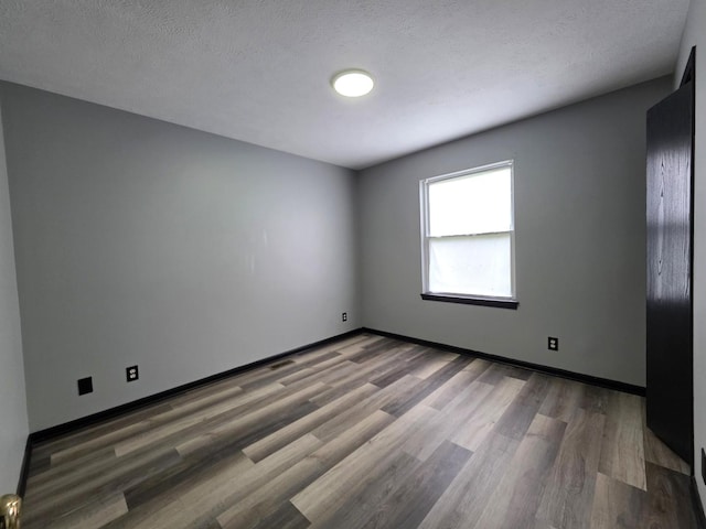 605 Tyler St, Genoa, IL 60135 - empty room with wood finished floors and a textured ceiling