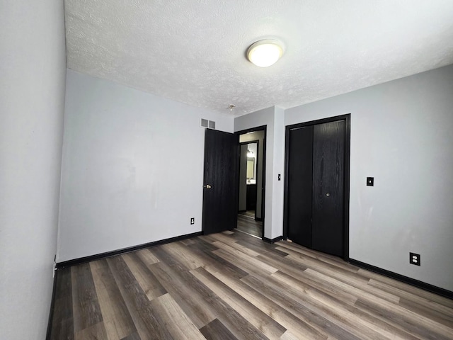 605 Tyler St, Genoa, IL 60135 - unfurnished bedroom featuring wood finished floors, a textured ceiling, and a closet