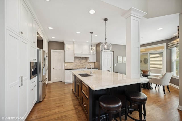 1613 Constitution Dr, Glenview, IL 60026 - kitchen with white cabinetry, backsplash, appliances with stainless steel finishes, a kitchen island with sink, and recessed lighting