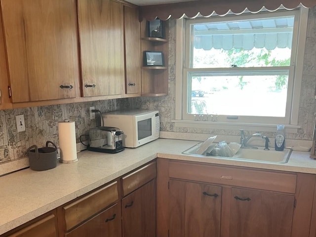 14 N Walnut St, Pesotum, IL 61863 - kitchen featuring light countertops, white microwave, brown cabinets, and decorative backsplash
