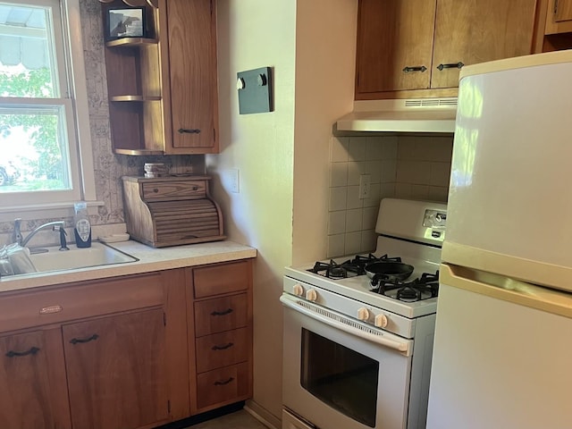 14 N Walnut St, Pesotum, IL 61863 - kitchen with white appliances, under cabinet range hood, backsplash, light countertops, and brown cabinetry
