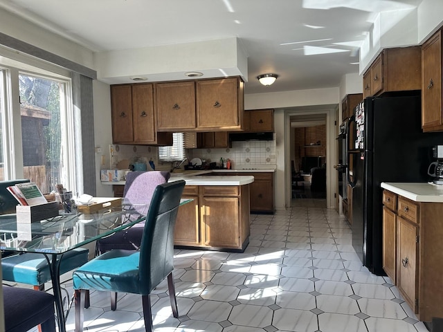56 Graymoor Ln, Olympia Fields, IL 60461 - kitchen with freestanding refrigerator, brown cabinetry, light countertops, under cabinet range hood, and backsplash