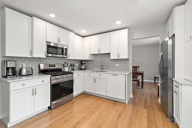 8941 Timothy Ct, Orland Park, IL 60462 - kitchen featuring appliances with stainless steel finishes, light countertops, tasteful backsplash, light wood-type flooring, and white cabinets