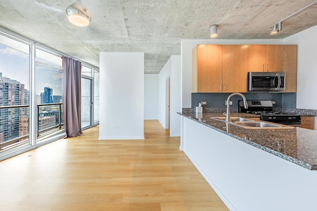611 S Wells St Unit 2301, Chicago, IL 60607 - kitchen featuring stainless steel appliances, light wood-style flooring, backsplash, and dark stone counters