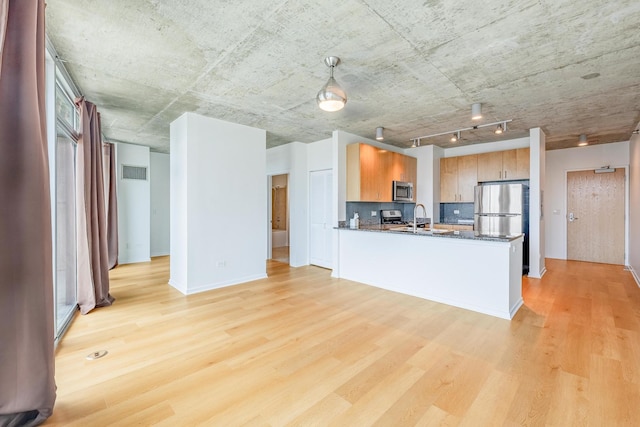 611 S Wells St Unit 2301, Chicago, IL 60607 - kitchen featuring appliances with stainless steel finishes, light wood-type flooring, a peninsula, dark stone countertops, and backsplash