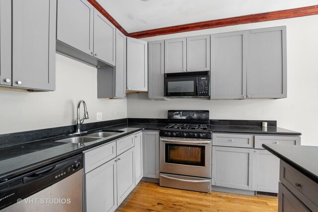 212 E 44th St Unit 2, Chicago, IL 60653 - kitchen with appliances with stainless steel finishes, light wood finished floors, gray cabinetry, and dark stone counters