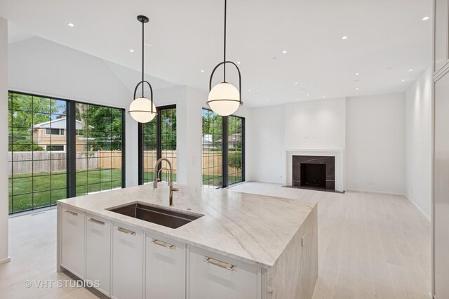 759 Strawberry Hill Dr, Glencoe, IL 60022 - kitchen with healthy amount of natural light, an island with sink, white cabinetry, light stone countertops, and recessed lighting