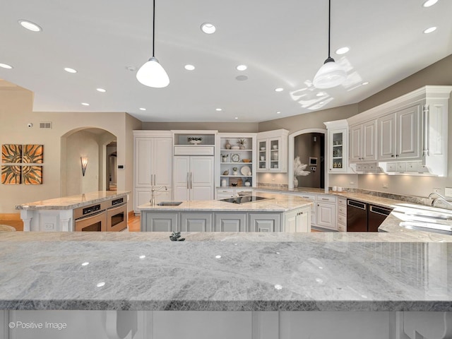 8698 S Madison St, Burr Ridge, IL 60527 - kitchen featuring arched walkways, a center island, black electric stovetop, light stone counters, and recessed lighting