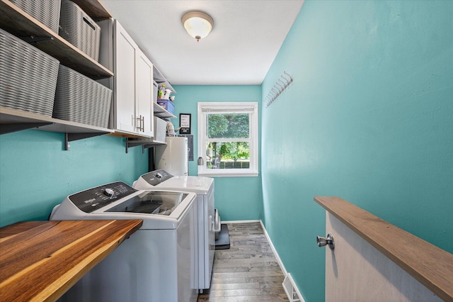 501 N Center St, Colfax, IL 61728 - laundry room with light wood-style floors, cabinet space, washing machine and dryer, and water heater
