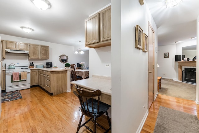 1937 Bayview Ln Unit 0, Aurora, IL 60506 - kitchen featuring white range with gas stovetop, under cabinet range hood, a peninsula, light wood finished floors, and a tile fireplace