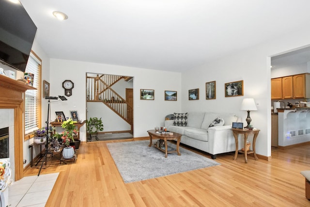 406 Kresswood Dr, Mchenry, IL 60050 - living room featuring stairway, light wood finished floors, and a tiled fireplace