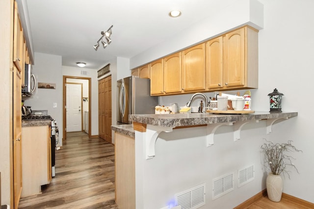 406 Kresswood Dr, Mchenry, IL 60050 - kitchen featuring stainless steel appliances, a breakfast bar area, wood finished floors, light brown cabinetry, and a peninsula