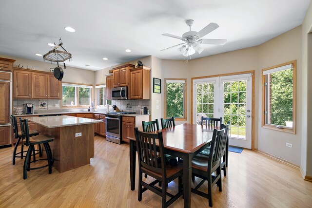 12532 Suffield Dr, Palos Park, IL 60464 - kitchen featuring appliances with stainless steel finishes, backsplash, a kitchen island, brown cabinetry, and a kitchen bar
