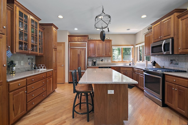 12532 Suffield Dr, Palos Park, IL 60464 - kitchen with stainless steel appliances, tasteful backsplash, a breakfast bar area, light wood-style flooring, and a center island