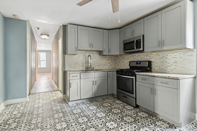 2345 S Lawndale Ave, Chicago, IL 60623 - kitchen with stainless steel appliances, gray cabinetry, decorative backsplash, light stone counters, and a ceiling fan
