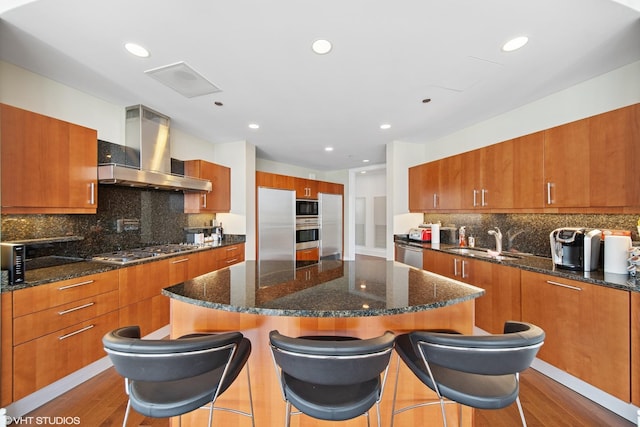 401 N Wabash St Unit 33A, Chicago, IL 60611 - kitchen featuring wall chimney range hood, stainless steel appliances, brown cabinetry, a kitchen island, and tasteful backsplash