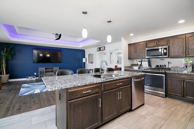 1867 Robert Dr, Bourbonnais, IL 60914 - kitchen featuring appliances with stainless steel finishes, a raised ceiling, dark brown cabinetry, light stone counters, and recessed lighting
