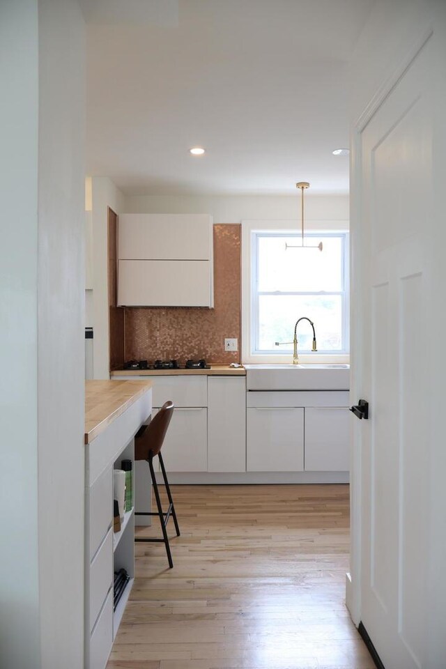 2913 N Kolmar Ave, Chicago, IL 60641 - kitchen featuring tasteful backsplash, white cabinets, light wood-style floors, recessed lighting, and decorative light fixtures