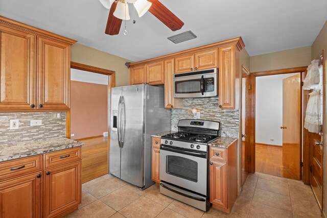 5144 W Saint Paul Ave, Chicago, IL 60639 - kitchen with stainless steel appliances, a ceiling fan, light stone counters, decorative backsplash, and light tile patterned floors