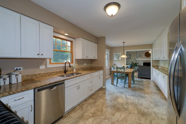 6S503 Bridlespur Dr, Naperville, IL 60540 - kitchen featuring appliances with stainless steel finishes, white cabinets, stone countertops, pendant lighting, and a fireplace