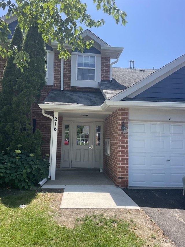 216 Charleston Ct Unit 8, Schaumburg, IL 60193 - view of front of home featuring brick siding, a shingled roof, a garage, and driveway