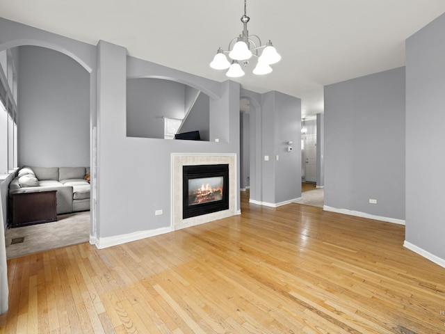 2019 Olde Mill Ln, Mchenry, IL 60050 - unfurnished living room featuring light wood-style floors, a chandelier, a fireplace, and arched walkways