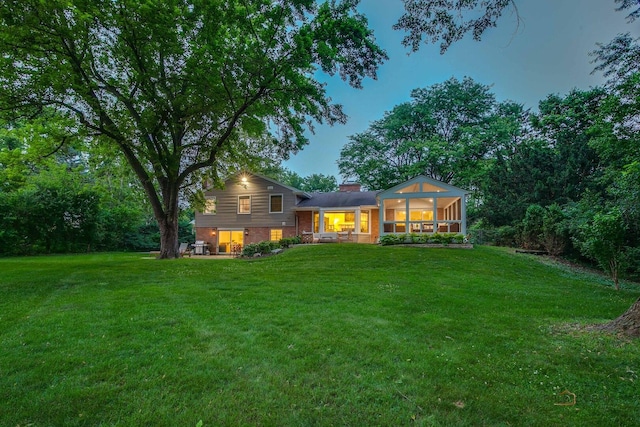 560 Golf Ln, Lake Forest, IL 60045 - rear view of house featuring a yard, a sunroom, a chimney, and brick siding