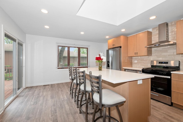 12123 S 72nd Ct, Palos Heights, IL 60463 - kitchen with appliances with stainless steel finishes, wall chimney range hood, light wood-style flooring, a breakfast bar area, and light countertops