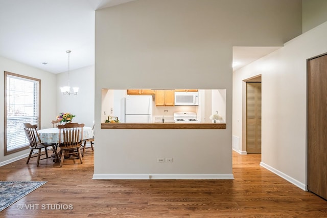 5145 Pembrook Ct, Gurnee, IL 60031 - kitchen featuring white appliances, wood finished floors, a chandelier, hanging light fixtures, and a towering ceiling