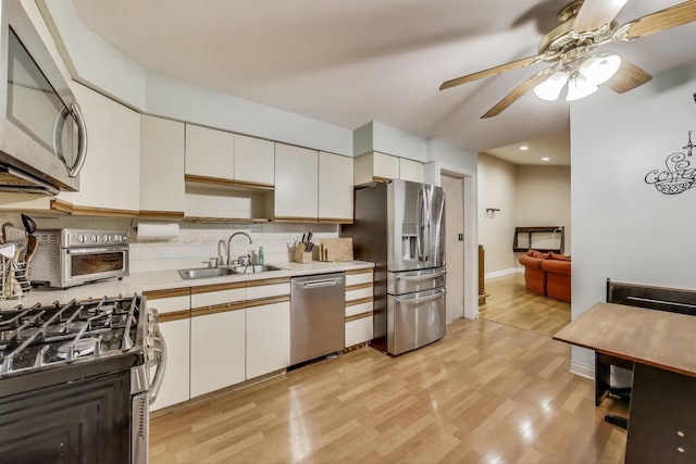 126 Oak Ave, Wood Dale, IL 60191 - kitchen with appliances with stainless steel finishes, a ceiling fan, light countertops, light wood finished floors, and backsplash