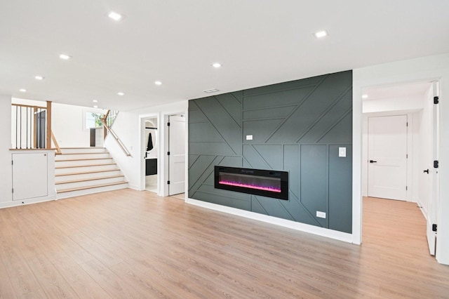 8127 Gross Point Rd, Morton Grove, IL 60053 - unfurnished living room featuring light wood-style floors, stairway, a fireplace, recessed lighting, and a decorative wall