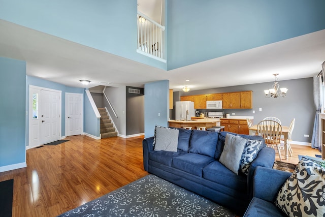 504 N Reef Rd, Lockport, IL 60441 - living room featuring stairs, a chandelier, light wood-style flooring, and a towering ceiling