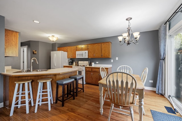504 N Reef Rd, Lockport, IL 60441 - kitchen with white appliances, a chandelier, a peninsula, brown cabinets, and light wood finished floors