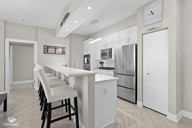 233 E 13th St Unit 2402, Chicago, IL 60605 - kitchen with appliances with stainless steel finishes, a breakfast bar area, white cabinetry, recessed lighting, and light countertops