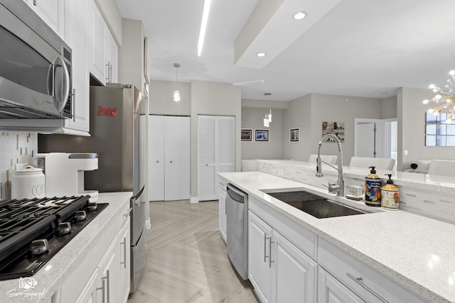 233 E 13th St Unit 2402, Chicago, IL 60605 - kitchen with stainless steel appliances, a chandelier, white cabinetry, light stone counters, and hanging light fixtures