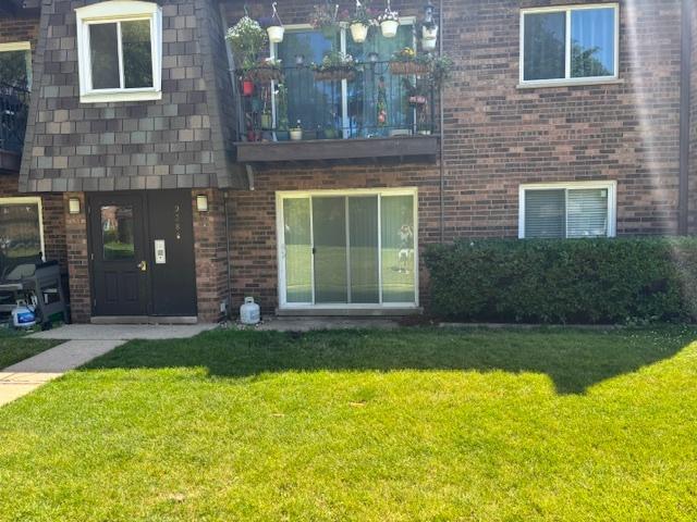 9388 Bay Colony Dr Unit 1S, Des Plaines, IL 60016 - property entrance with brick siding, a lawn, and a balcony